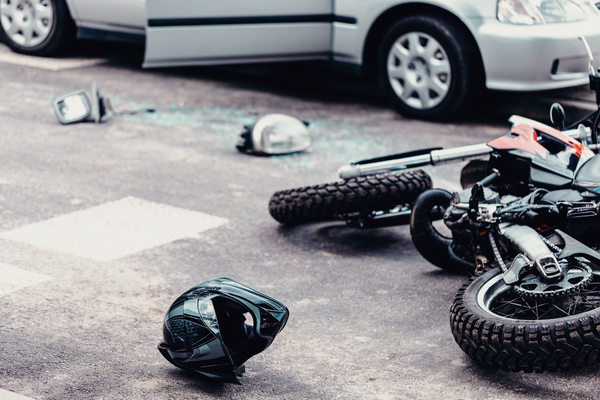 A helmet and motorcycle next to broken pieces of car damaged due to accident