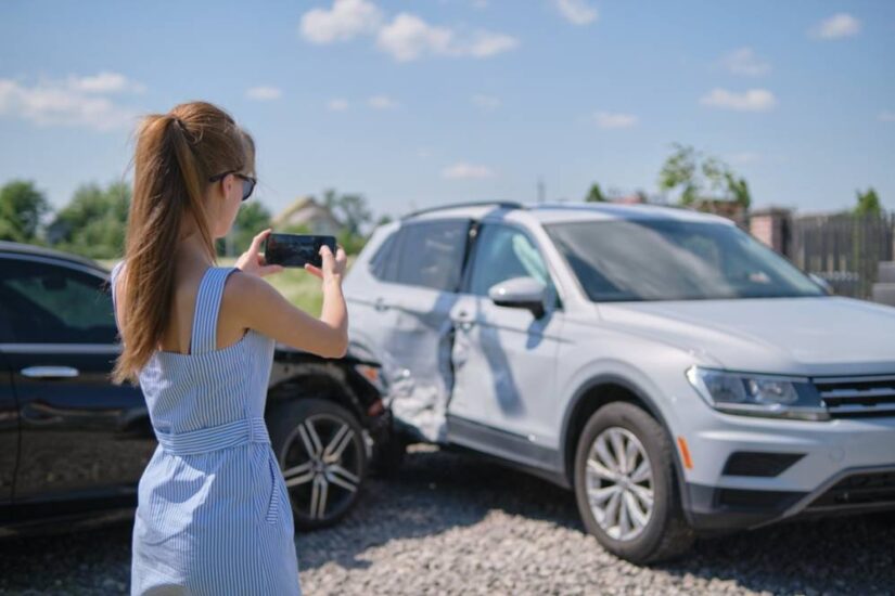 Photo of a girl taking pictures of damaged car